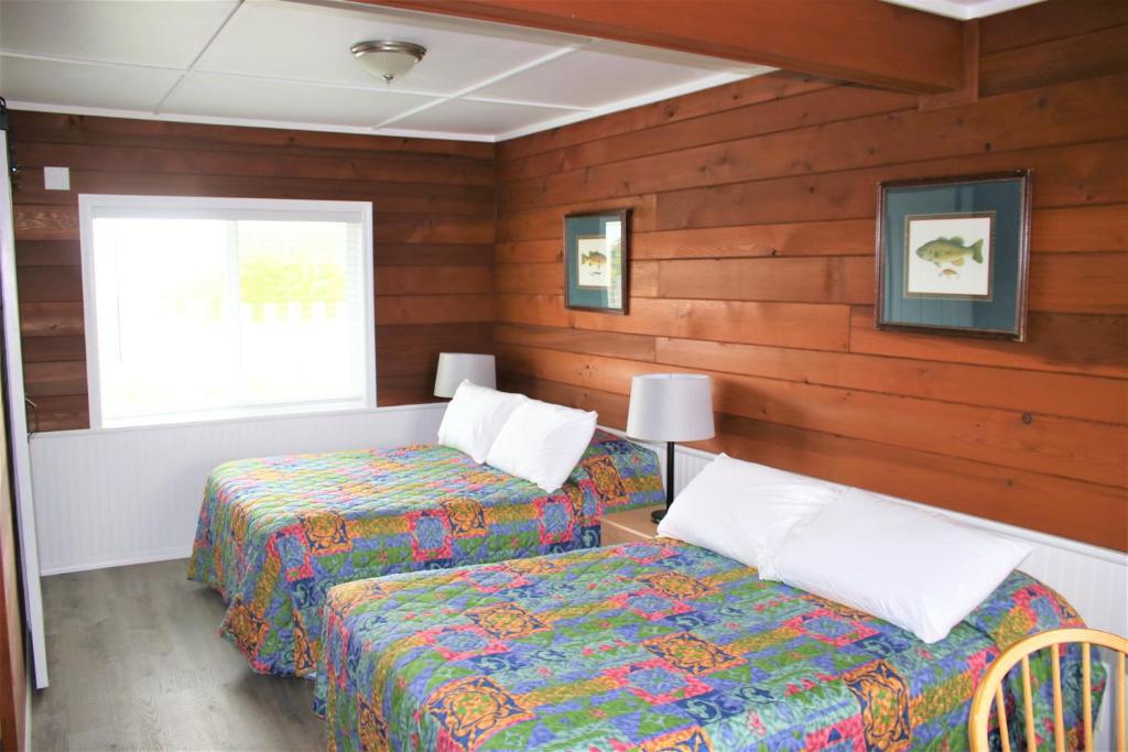 two beds in a room with wooden walls at The Lowtide Motel in Copalis Beach