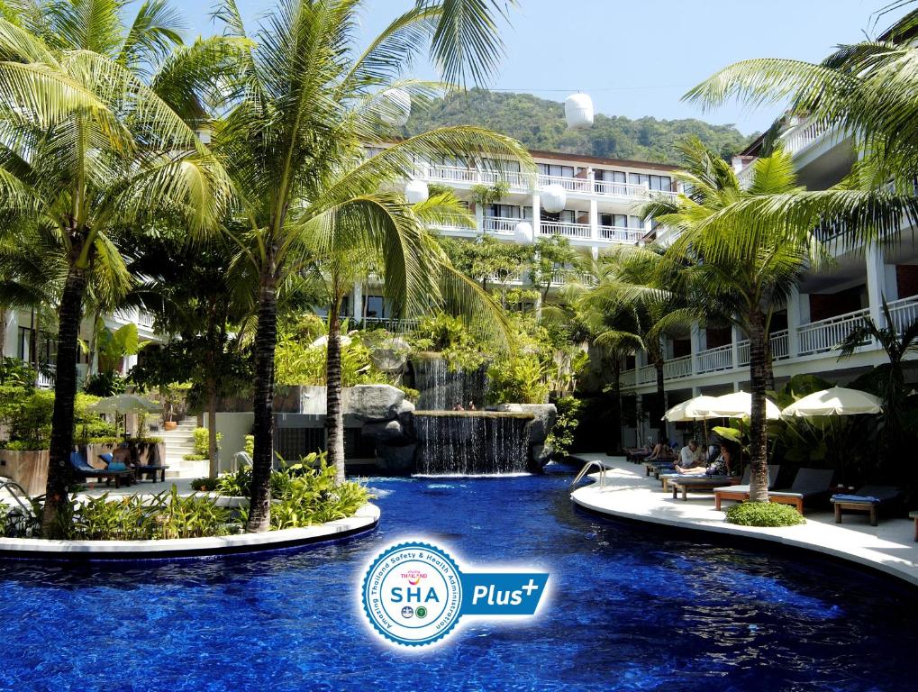a resort swimming pool with palm trees and a hotel at Sunset Beach Resort - SHA Extra Plus in Patong Beach