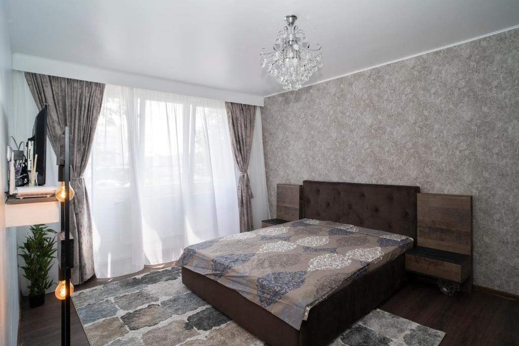a bedroom with a bed and a chandelier at Garsoniera LUX Drumul Taberei in Bucharest