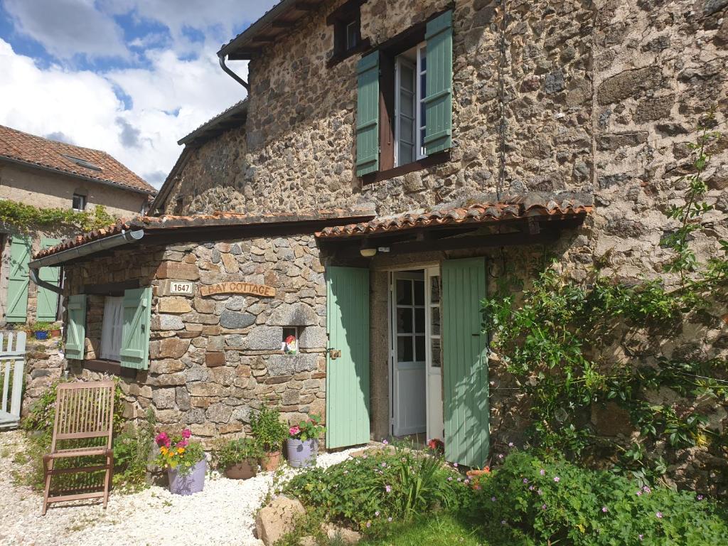 a stone house with a green door and a chair at Bay Cottage Gite, Busserolles. in Busserolles