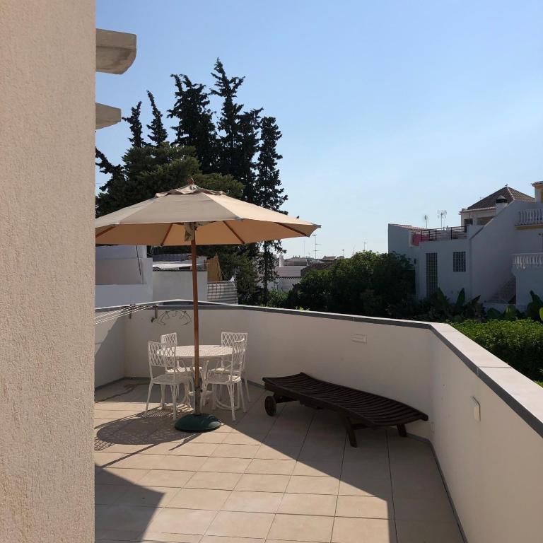 a patio with a table and an umbrella and a bench at Sossego Salgado in Tavira