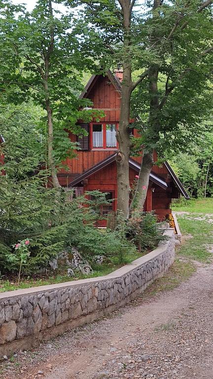 a log cabin with a stone wall in front of it at Kuća za odmor "Med Strmci" in Zlobin