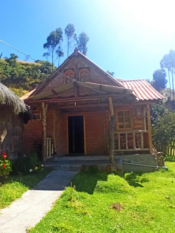 a wooden house with a pathway in front of it at Hostal La Rosita Guayama- Quilotoa in Quilotoa