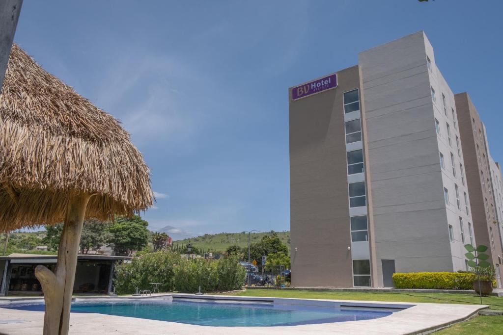 um hotel com um guarda-chuva de palha e um edifício em BV Hotel Atlixco em Atlixco