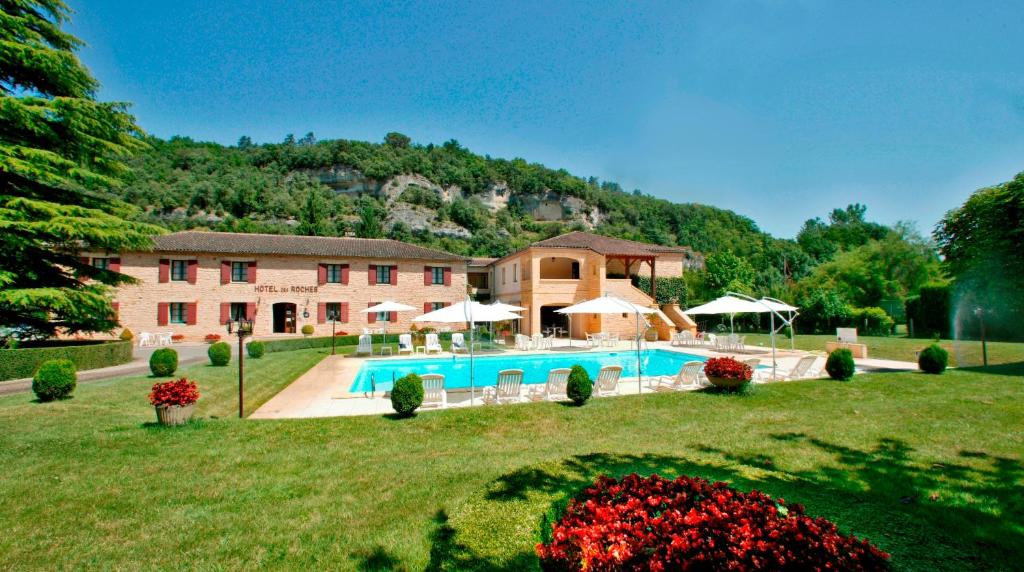 une grande maison avec une piscine dans une cour dans l'établissement Hôtel des Roches - Climatisation, à Les Eyzies-de-Tayac