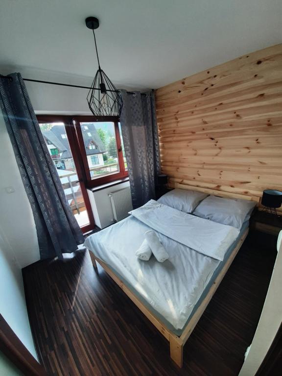a large bed in a room with a wooden wall at Laura's Apartments in Zakopane