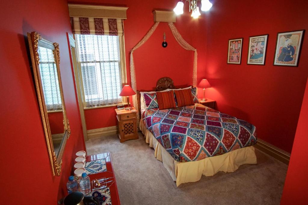 a bedroom with red walls and a bed with a mirror at Sea Breeze B & B in Napier