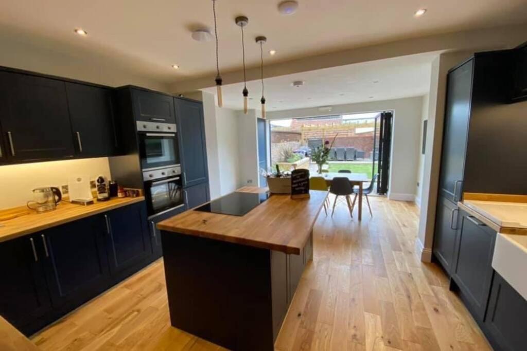 a kitchen with black cabinets and a wooden counter top at WESTREACH Filey - a 4 Bedroom, all en-suite sleep 8 Townhouse in Filey