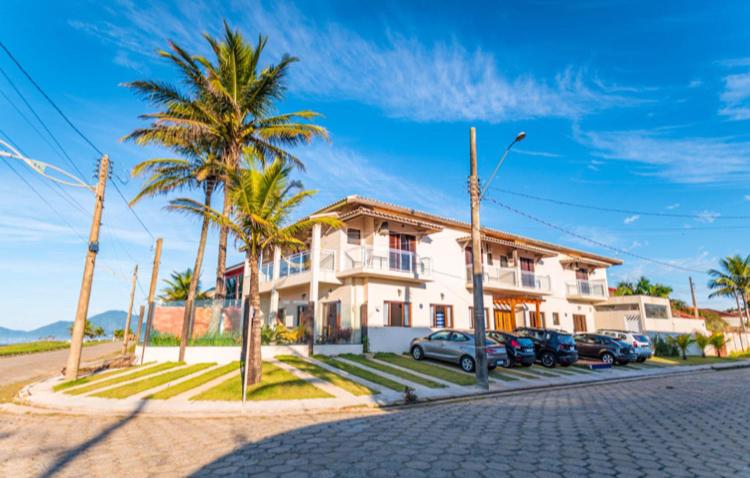a house with palm trees in front of a street at Mar Egeu Arte & Pouso in Peruíbe