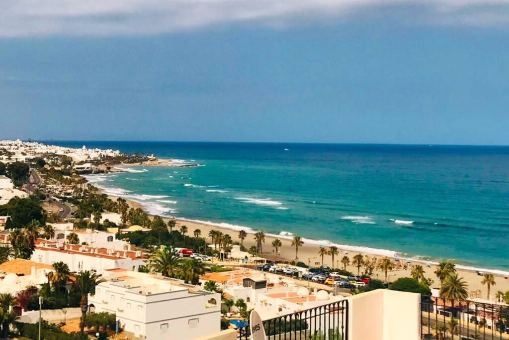 Blick auf einen Strand mit Palmen und das Meer in der Unterkunft Penthouse with large terrace and roof solarium, with amazing sea views in Mojácar