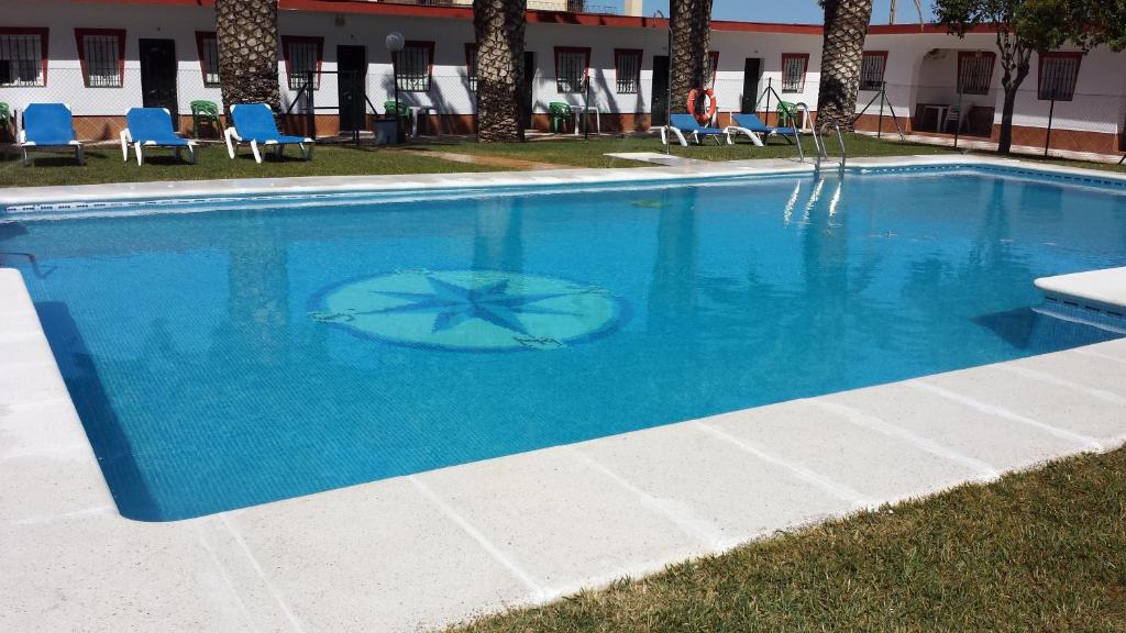 una gran piscina azul con sillas y un edificio en Apartamentos Las Parcelas, en Conil de la Frontera