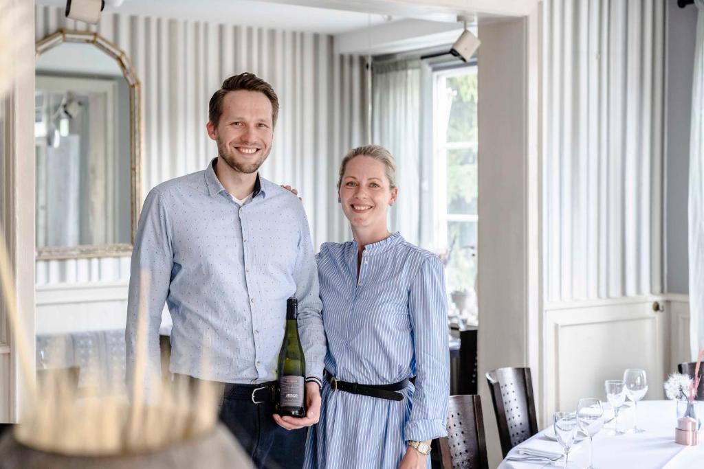 a man and a woman holding a bottle of wine at Flair Hotel Zur Eiche in Buchholz in der Nordheide