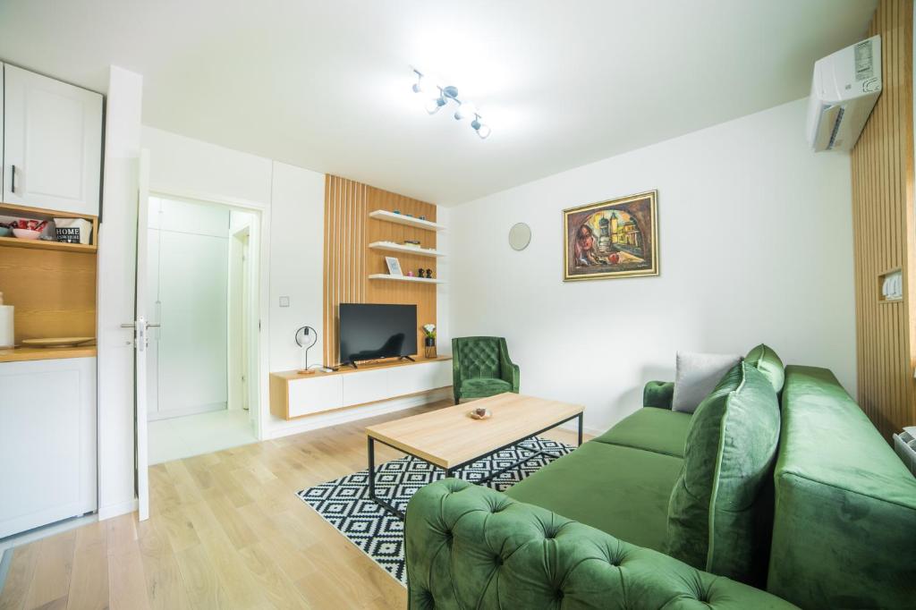 un soggiorno con divano verde e tavolo di Liberty Apartments a Tuzla