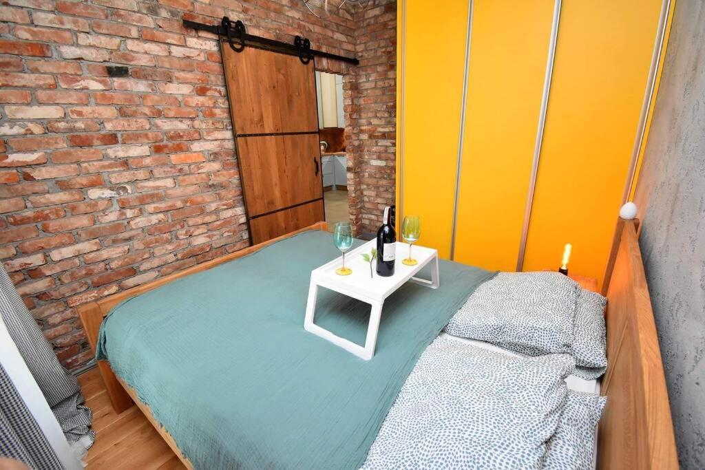 Habitación con cama con mesa y pared de ladrillo en Apartament Blue Bastion Wałowa 23c z klimatyzacją i miejscem parkingowym w podziemnym parkingu, en Gdansk
