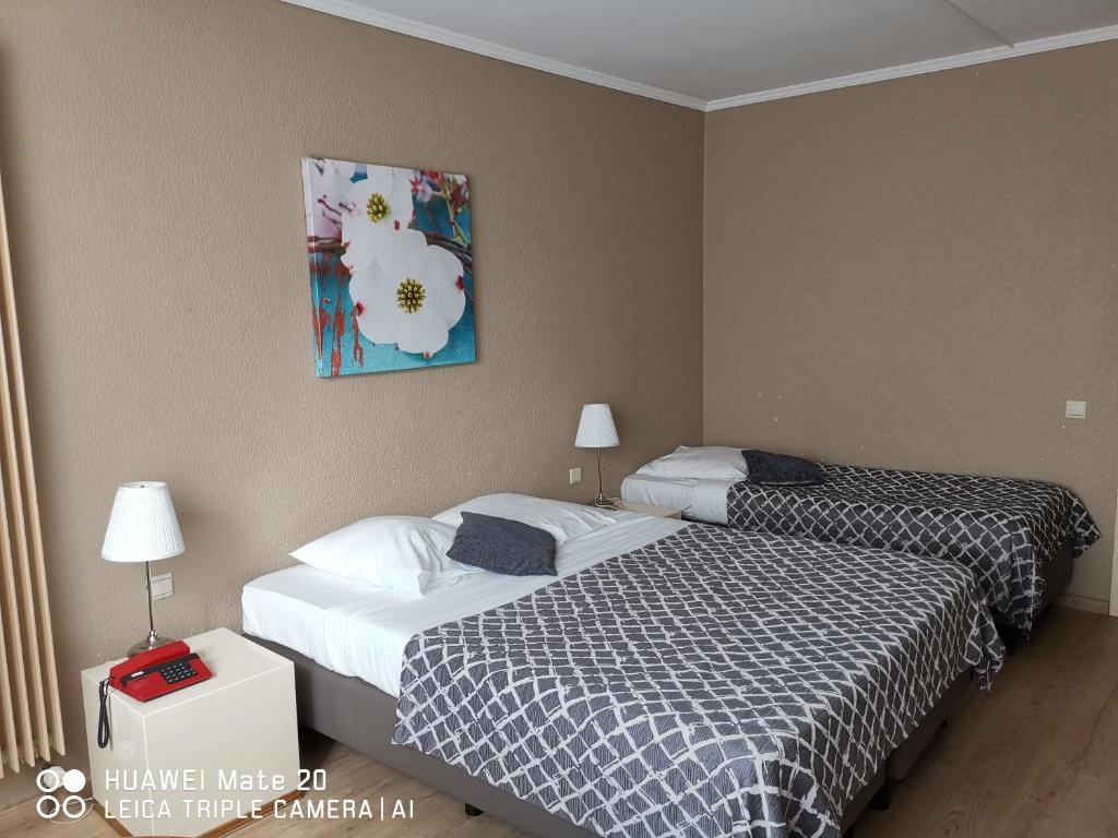a hotel room with two beds and a painting on the wall at Hôtel La Côte d'Or in Philippeville