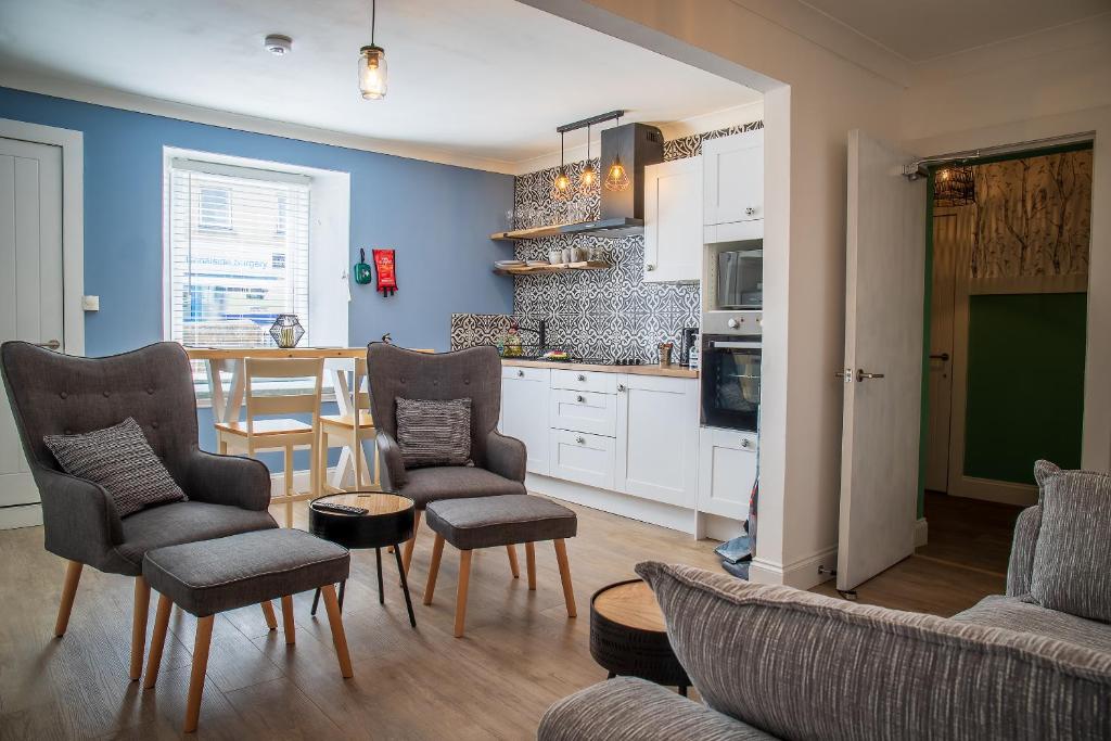 a living room with a couch and chairs and a kitchen at Great Glen Way Canal Side Apartment in Inverness