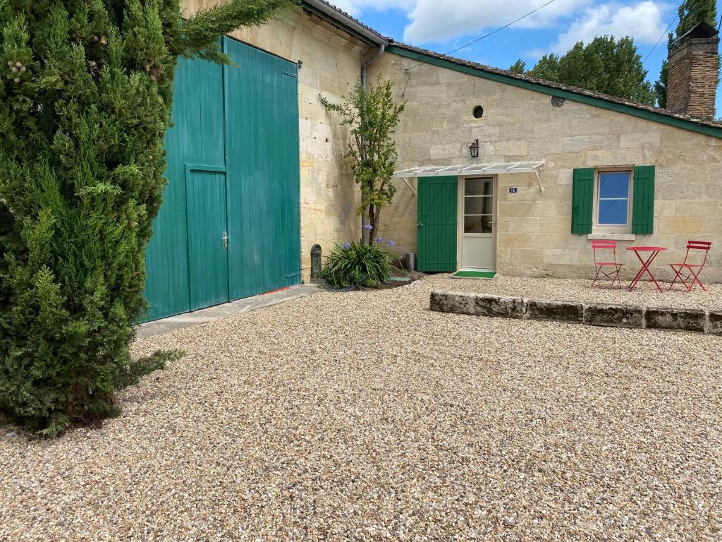 a building with a green garage door and two red chairs at 16 CHEMIN DE BOISBELET in Coutras