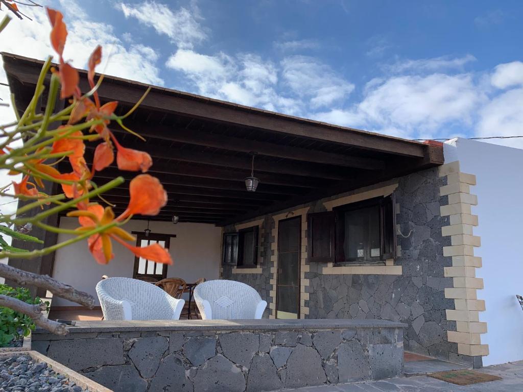une maison avec des chaises blanches et un chien sur la terrasse couverte dans l'établissement El Remanso, à Pájara