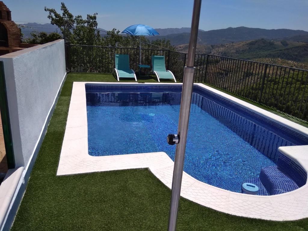 a swimming pool with chairs next to a house at La Revuelta in Yunquera