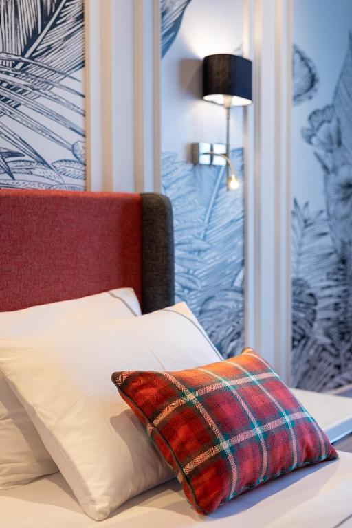 a bed with a plaid pillow on top of it at Motif Hotel Çeşme in Çeşme