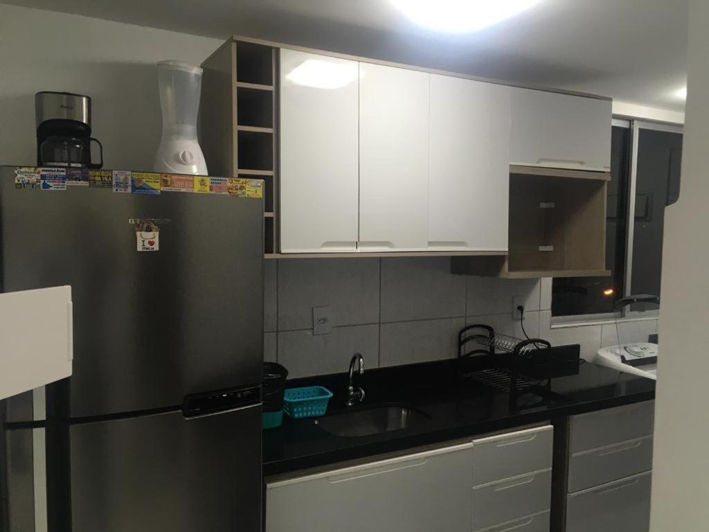 cocina con armarios blancos y nevera de acero inoxidable en Alugo apartamento perto de Porto de Galinhas en Ipojuca