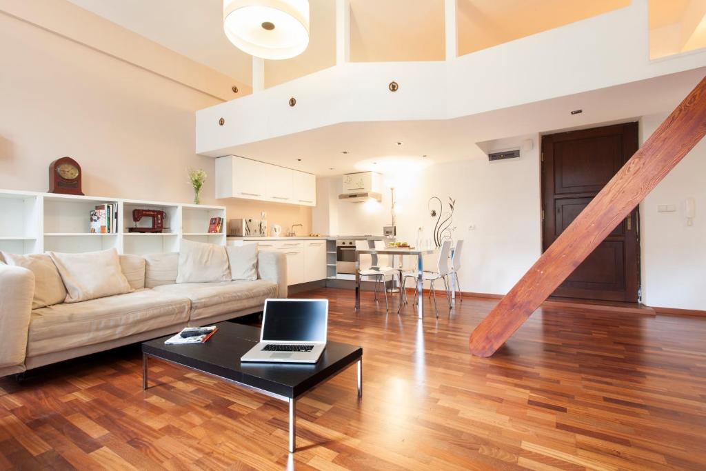een woonkamer met een bank en een tafel met een laptop bij DaVinci Radziwiłłowska Apartments in Krakau