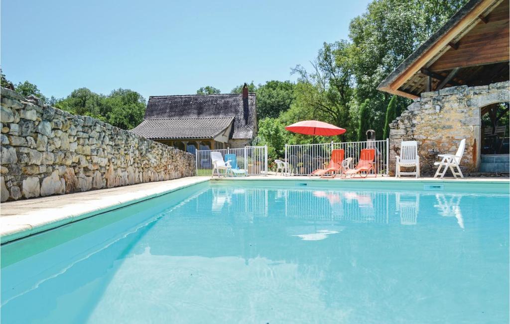 a swimming pool with chairs and an umbrella at Awesome Home In Padirac With Kitchenette in Padirac