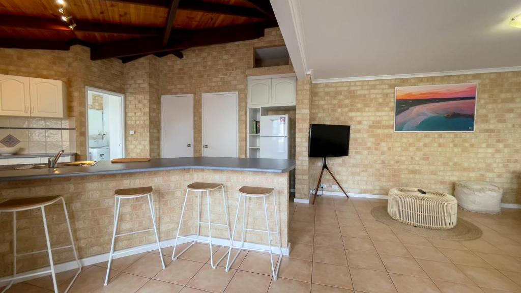 a kitchen with a counter and stools in a room at Esperance Foreshore Apartments in Esperance