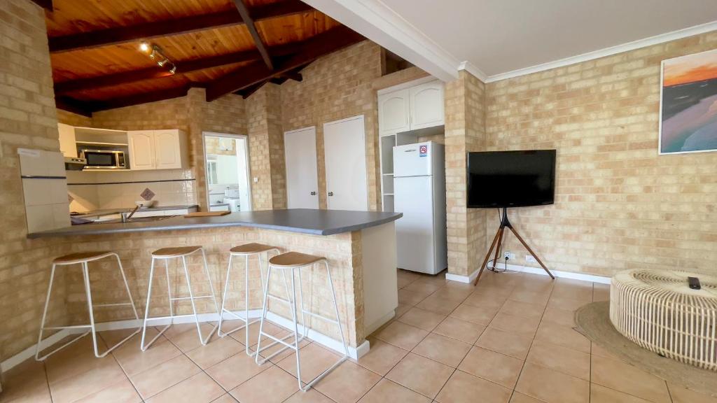 a kitchen with a counter with stools and a television at Esperance Foreshore Apartments in Esperance