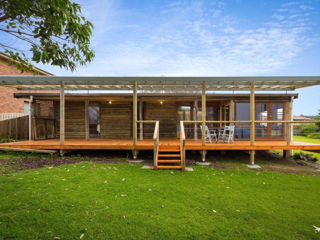 ein großes Holzhaus mit einer großen Terrasse in der Unterkunft 98 Ocean Parade Rustic Log Cabin in Dalmeny