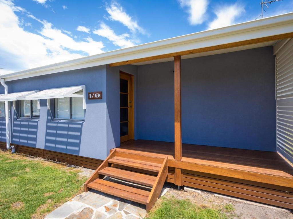 a blue house with a wooden deck on it at The Inlet Cottage in Narooma