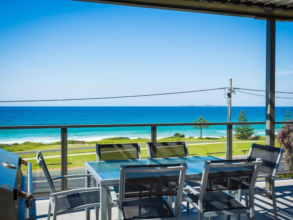 
a patio area with chairs, tables, chairs and umbrellas at 81 Dalmeny Drive - Beach House in Kianga
