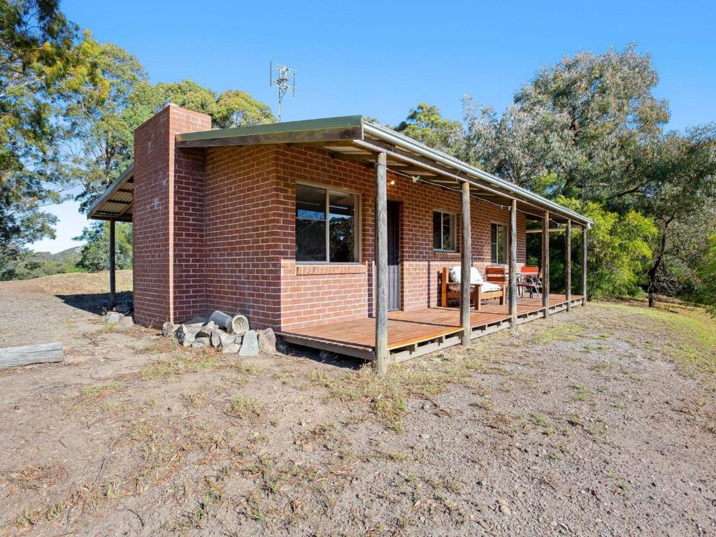 a brick house with a porch on a field at Braeside Cabin Four Ziera in Central Tilba