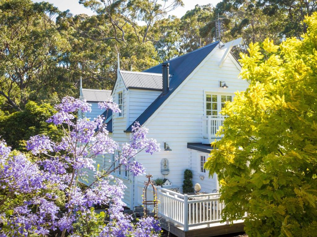 a white house with purple flowers in front of it at The Cottage in Kianga