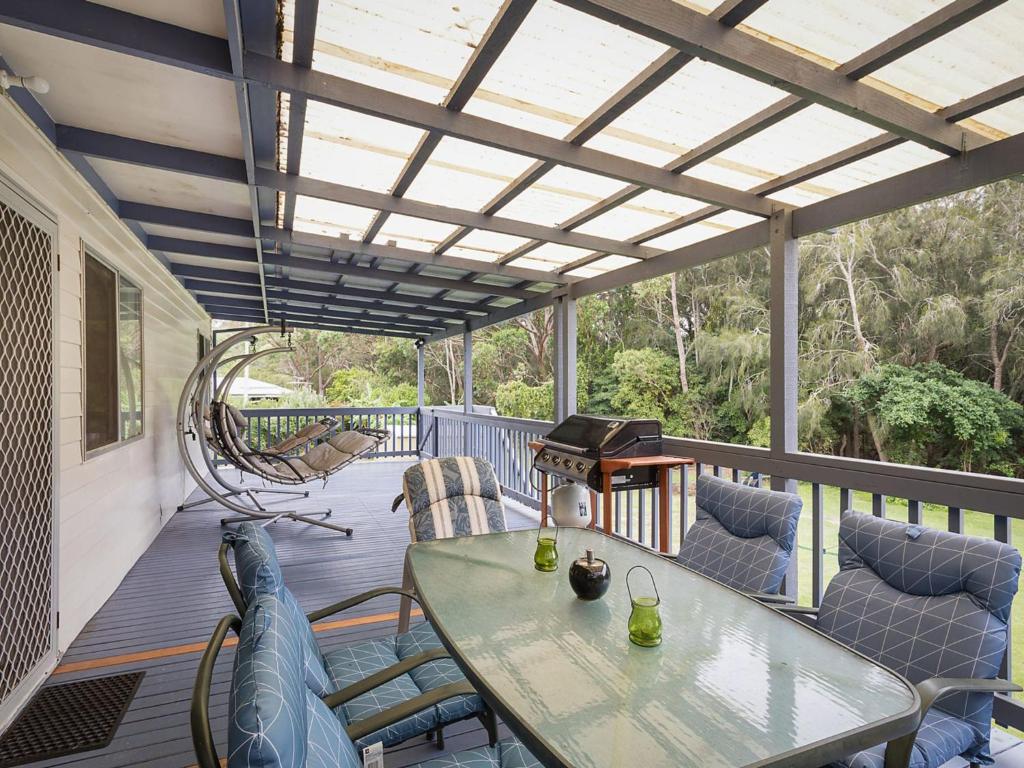 a patio with a table and chairs on a deck at Pet friendly Beach House at Kianga in Kianga