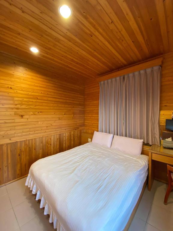 a bedroom with a bed in a wooden room at Tianyi Homestay in Fenqihu