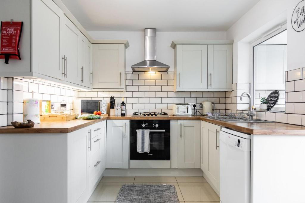 a kitchen with white cabinets and a stove top oven at Maunsell House - Lovely central home near Designer Outlets & town with parking in Ashford