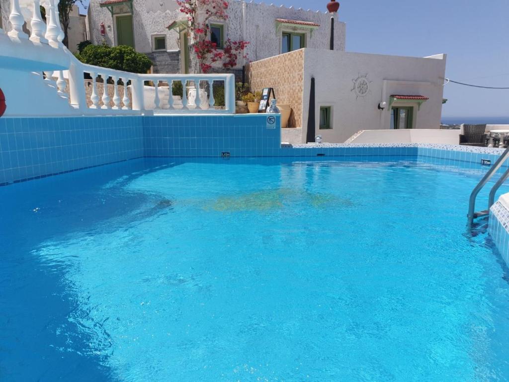 a swimming pool with blue water in front of a house at Executive Junior Suite in Hersonissos
