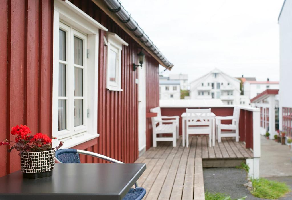 a balcony with a table and chairs on a house at Fiskekrogen Rorbuer in Henningsvær