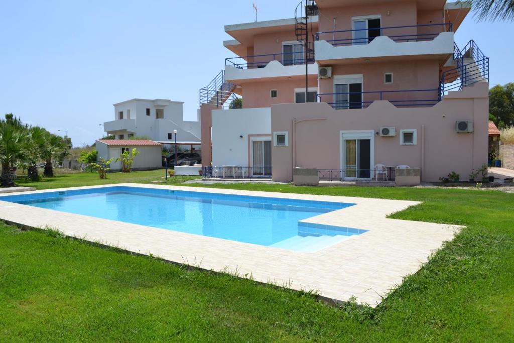 a villa with a swimming pool in front of a house at Petasos Apartments 1 in Gennadi