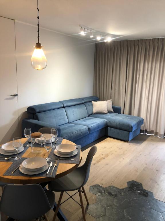 een woonkamer met een blauwe bank en een tafel bij Apartament Blue Sea in Międzywodzie