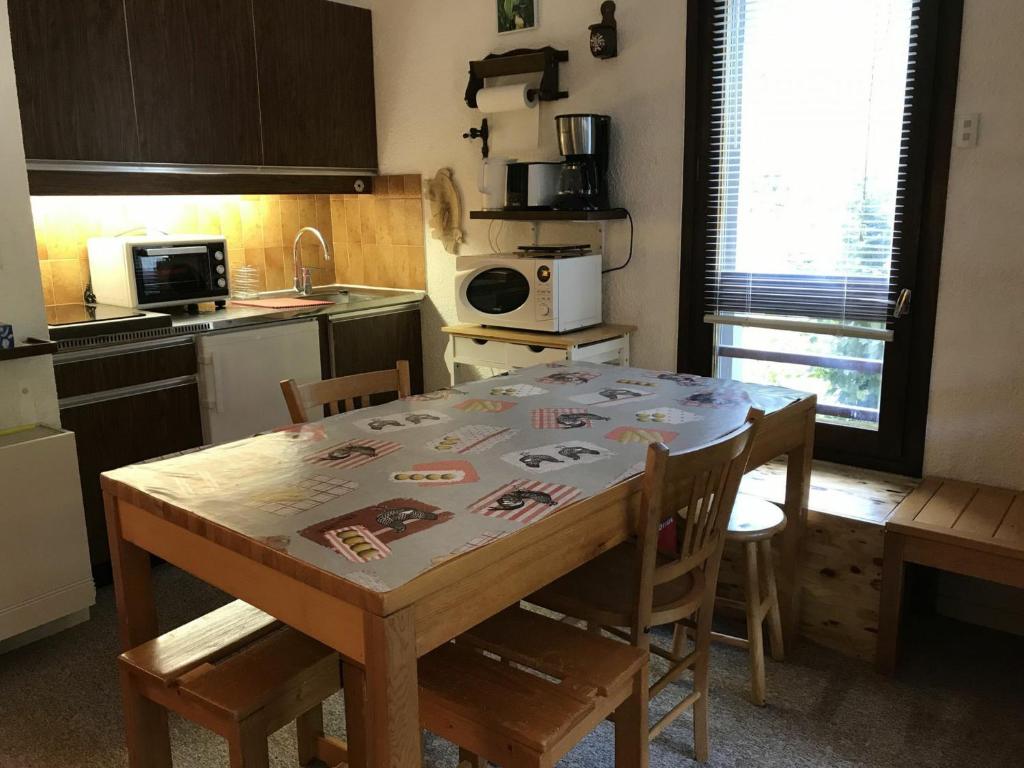 una cucina con tavolo in legno, sedie e tavolo e una cucina con di Studio Corrençon-en-Vercors, 1 pièce, 4 personnes - FR-1-515-92 a Corrençon-en-Vercors