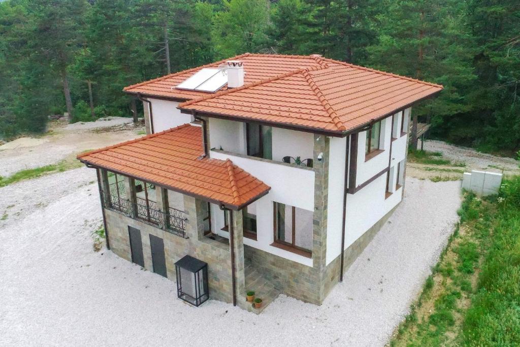 una piccola casa con un tetto arancione su una spiaggia di Къща за гости Синята Врана a Mostowo
