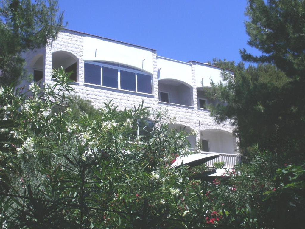 un edificio de ladrillo blanco con árboles delante de él en Apartments Gilve, en Hvar