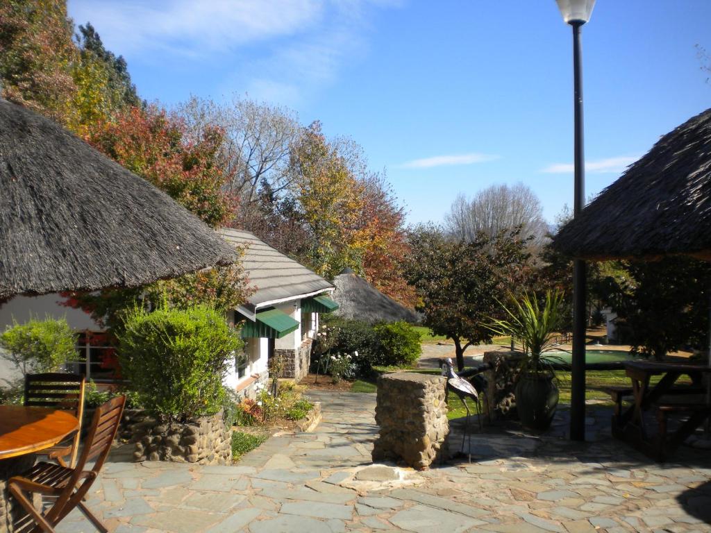 a patio with a table and a thatch roof at Himeville Arms in Himeville