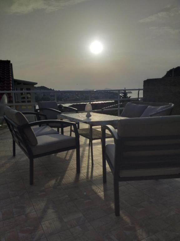 a table and chairs on a balcony with the sun setting at Apartments & Rooms Abba in Dubrovnik