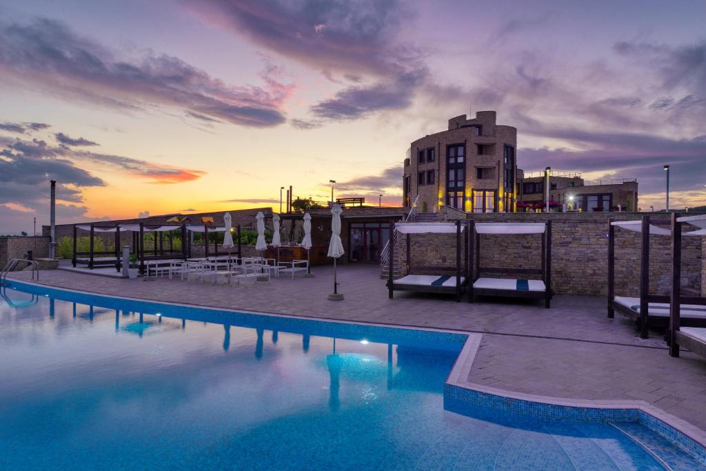 a large swimming pool with a sunset in the background at Hotel Soli Invicto in Elenovo