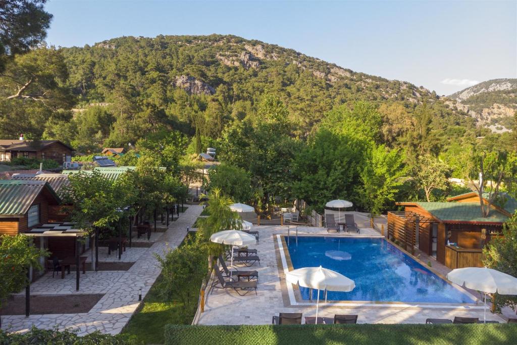 an outdoor swimming pool with tables and umbrellas at Koala Bungalows in Olympos