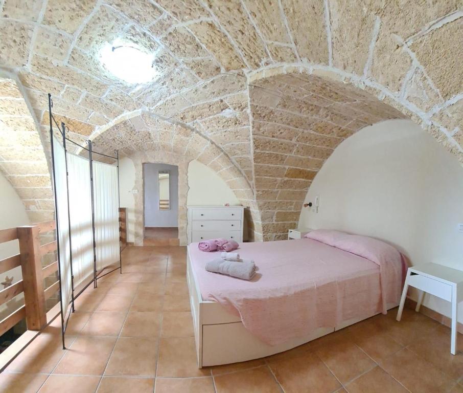 マティーノにあるCasa Costaのレンガの壁に大きなベッドが備わるベッドルーム1室が備わります。