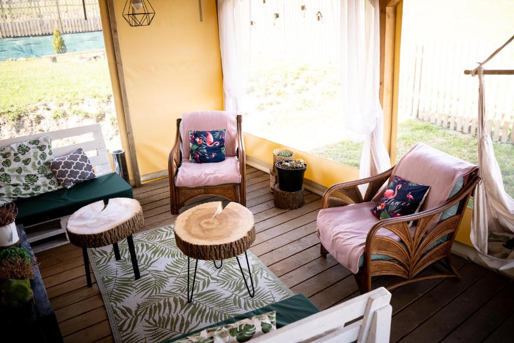 a screened in porch with two chairs and a couch at Bieszczadzkie BOHO stodoły z jacuzzi i sauna na wyłączność in Myczkowce